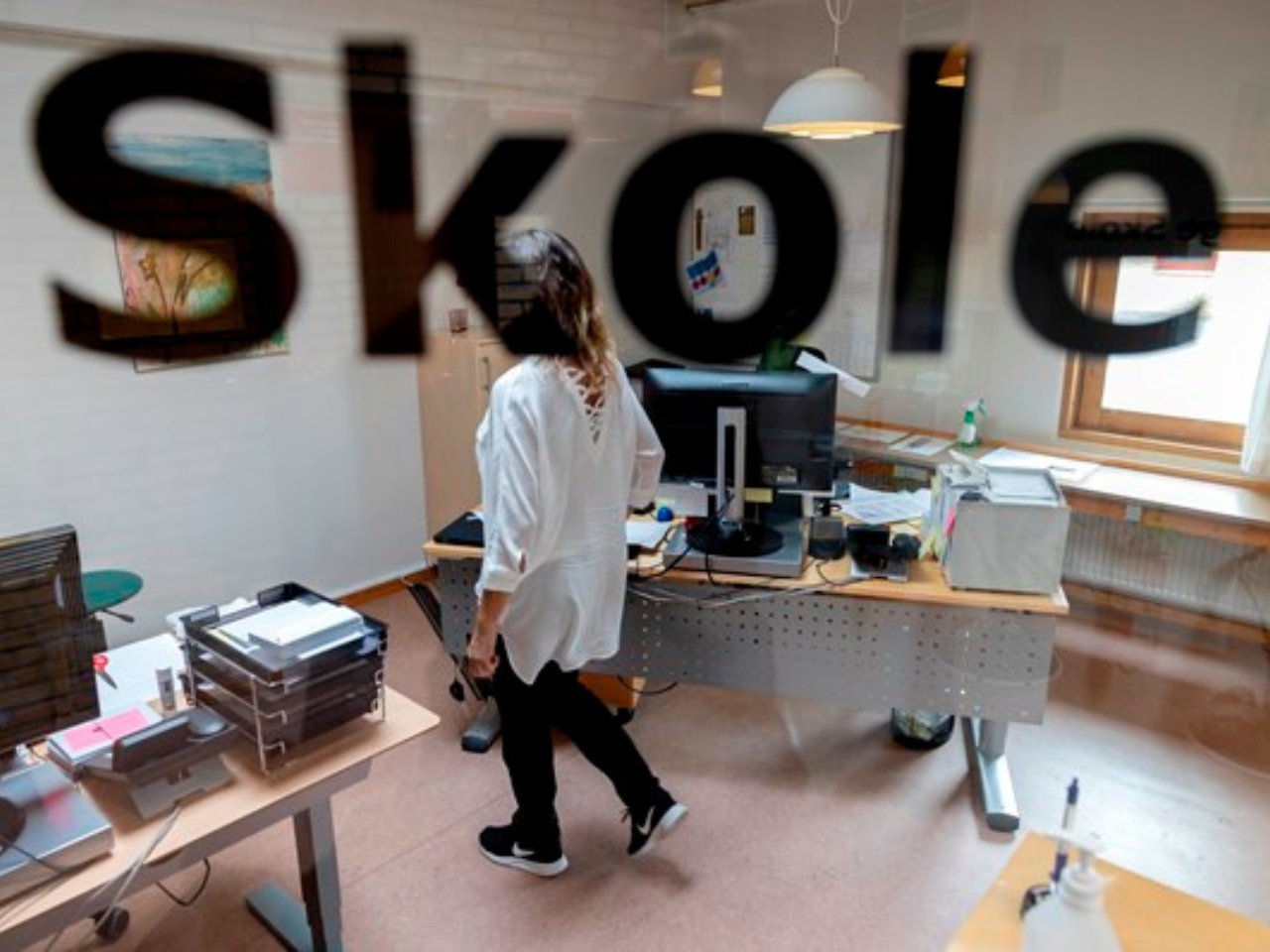 kvinde på kontor set gennem en rude hvor der står: 