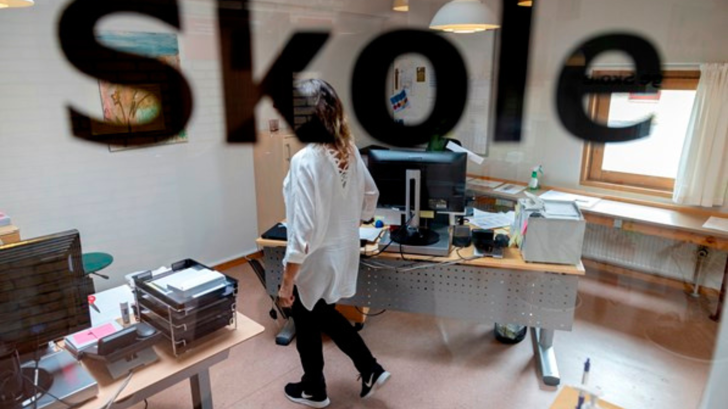 kvinde på kontor set gennem en rude hvor der står: 