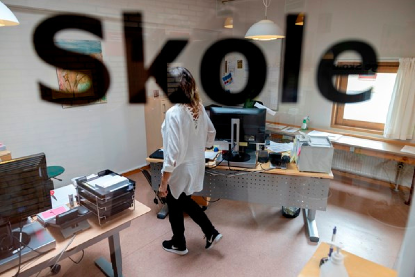 kvinde på kontor set gennem en rude hvor der står: 